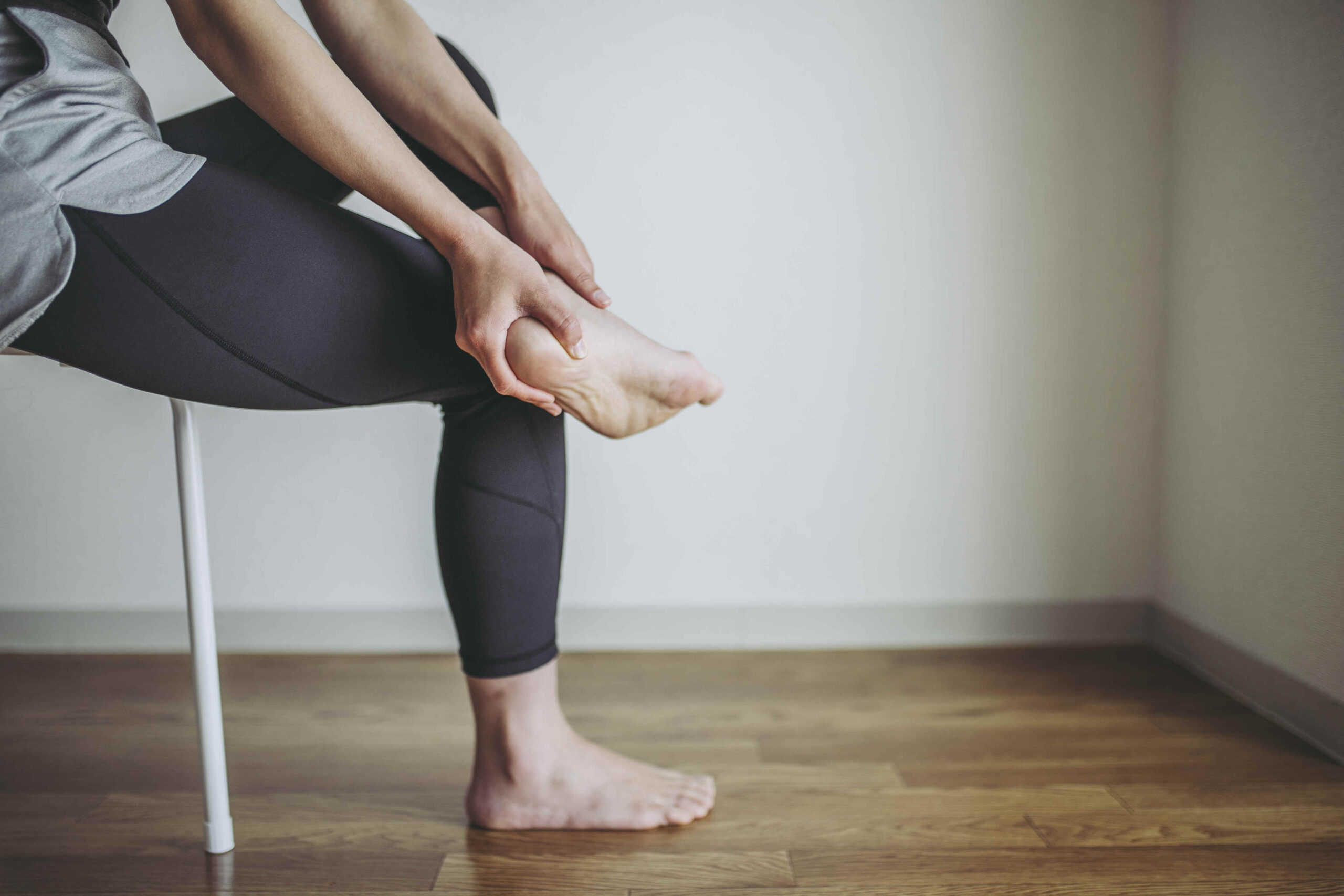 Young woman in sports leggings walks barefoot on the warm floor in